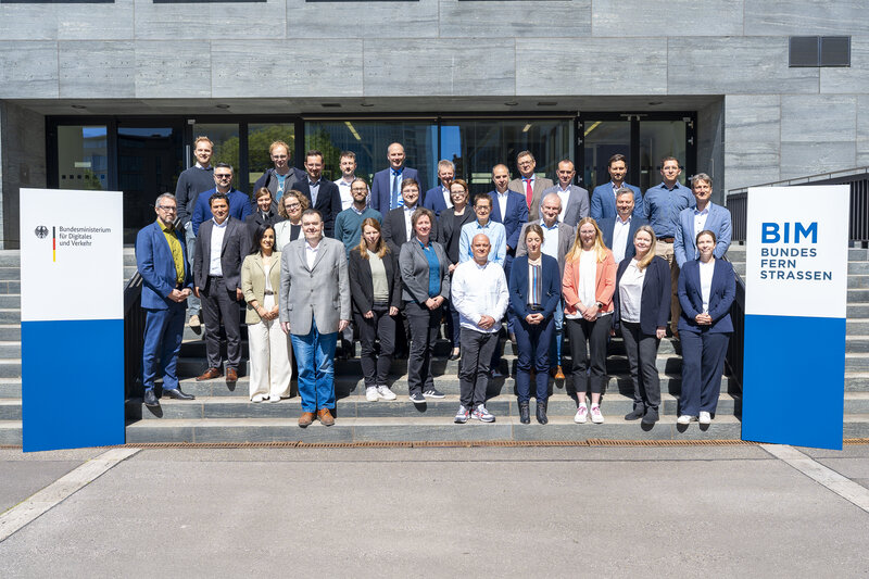 Gruppenfoto der Teilnehmenden der Bund-/Länder-Dienstbesprechung auf den Treppenstufen vor dem Bundesministerium für Verkehr, flankiert von zwei Aufstellern mit Logo des Ministeriums und BIM Bundesfernstraßen