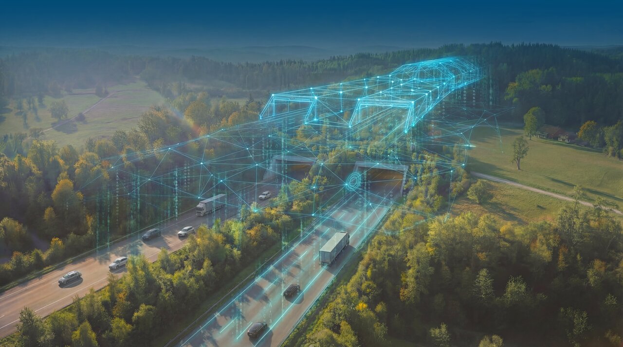 Luftaufnahme einer Autobahn durch eine bewaldete Landschaft. Darüber liegt eine leuchtend blaue digitale Liniengrafik, die Tunnel, Brücken und Verkehrswege als vernetztes Datenmodell darstellt.