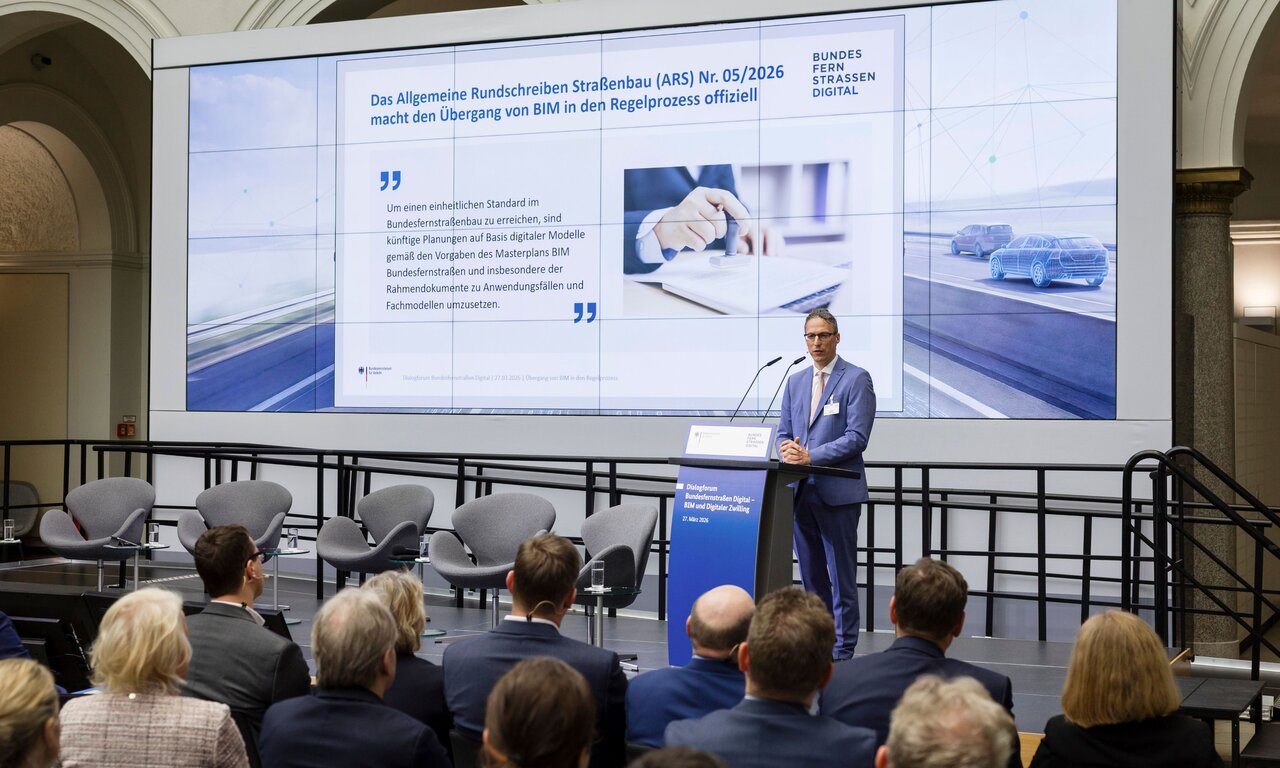 MDirig Steffen Müller, Leiter der Unterabteilung Straßen- und Ingenieurbau im Bundesministerium für Verkehr, beim Dialogforum Bundesfernstraßen Digital am 26. März 2026, im Hintergrund: Präsentationsfolie zum Allgemeinen Rundschreiben Straßenbau Nr. 05/2026
