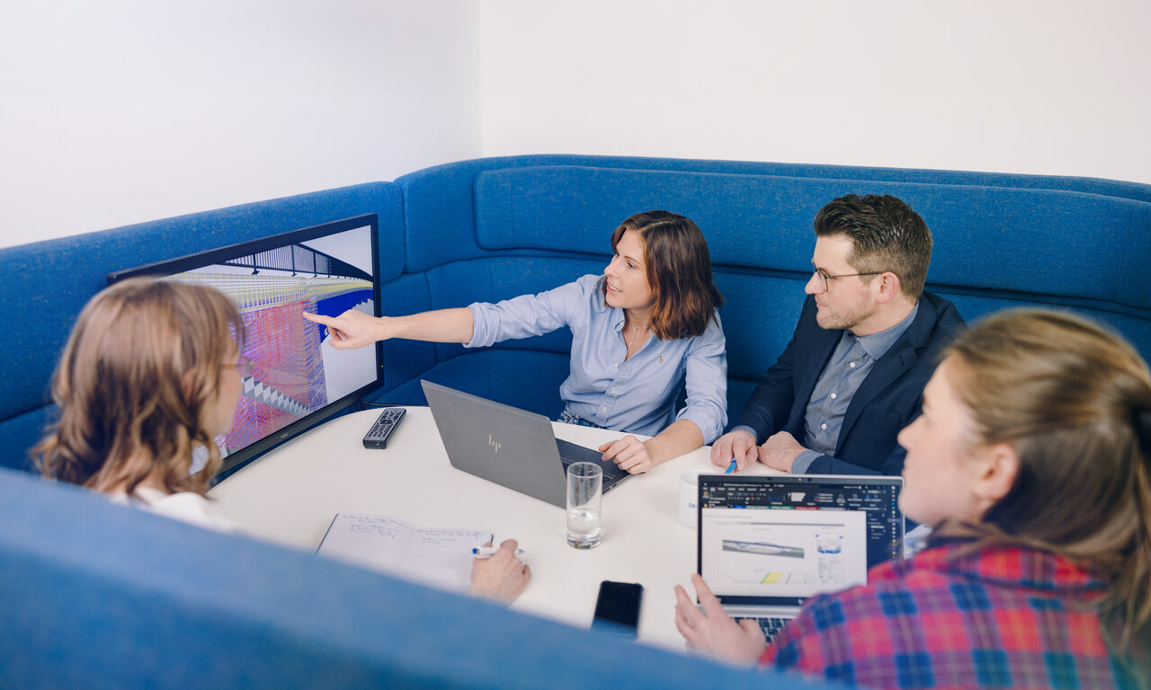 Eine Gruppe von Planenden diskutiert und blickt dabei auf einen Bildschirm mit der Darstellung aus einem BIM-Modell