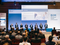 Podiumsdiskussion, Teilnehmende sind über die Köpfe des Publikums hinweg auf der Bühne zu sehen 