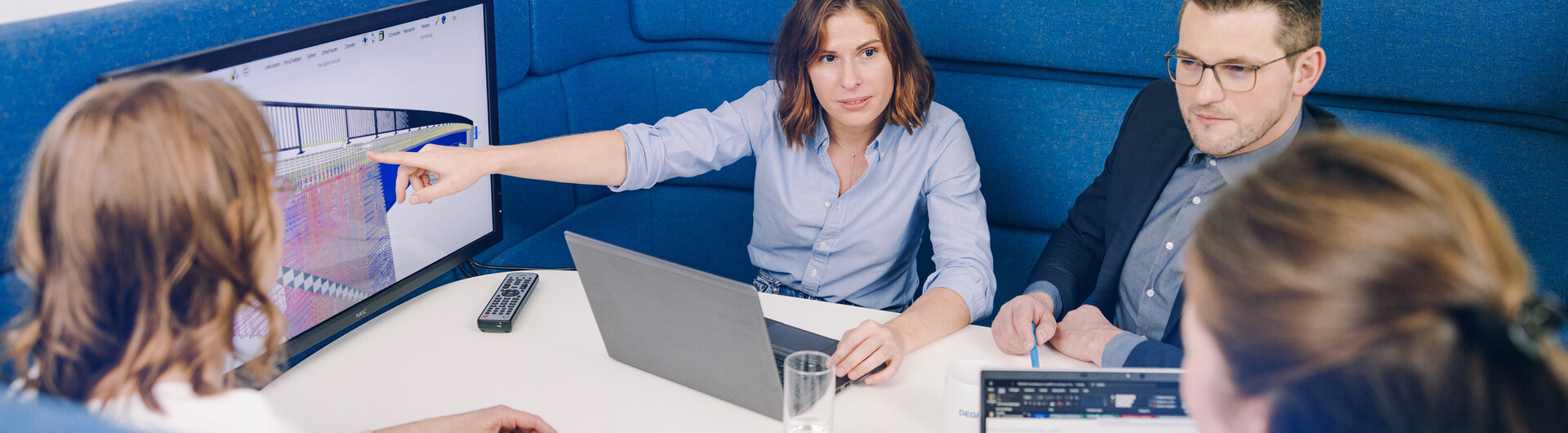 Eine Gruppe von Planenden diskutiert und blickt dabei auf einen Bildschirm mit der Darstellung aus einem BIM-Modell