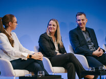 Drei freundlich lächelnde Teilnehmende einer Panel-Runde
