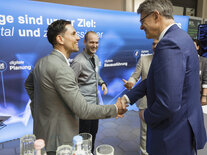 Bundesverkehrsminister Patrick Schnieder und ein Teilnehmender des Dialogforums Bundesfernstraßen Digital reichen sich die Hand