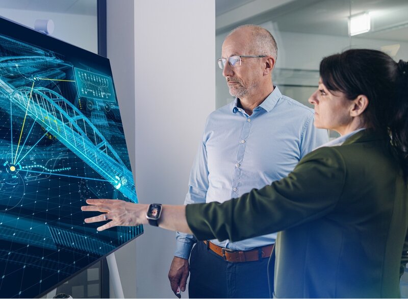 Ein Mann und eine Frau deuten auf einen Bildschirm mit einem digitalen Bauwerksmodell