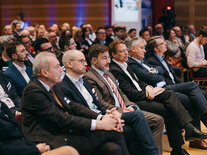 Die erste Reihe des Publikums, alle Stühle sind von aufmerksam blickenden Teilnehmern belegt