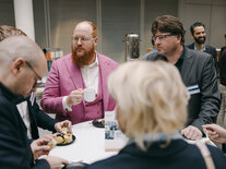 Vier Männer und eine Frau am Stehtisch im Gespräch während der Mittagspause