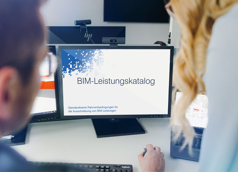 Zwei Personen blicken auf einen Monitor, auf dem das Titelblatt des BIM-Leistungskatalogs gezeigt wird.