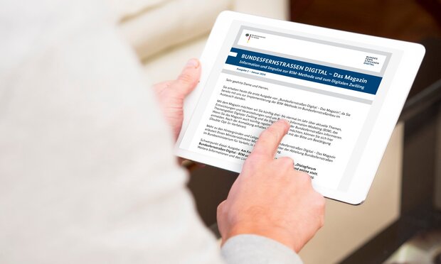 Person hält ein Tablet-Computer in den Händen und liest auf diesem den Newsletter "Bundesfernstraßen Digital - Das Magazin"
